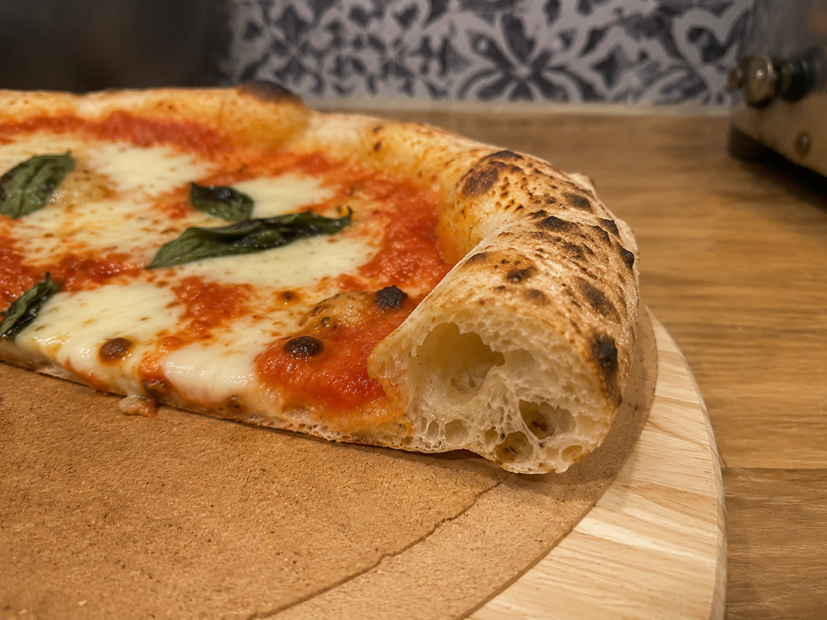 Fatia de pizza artesanal da Casa Serenità, com borda aerada